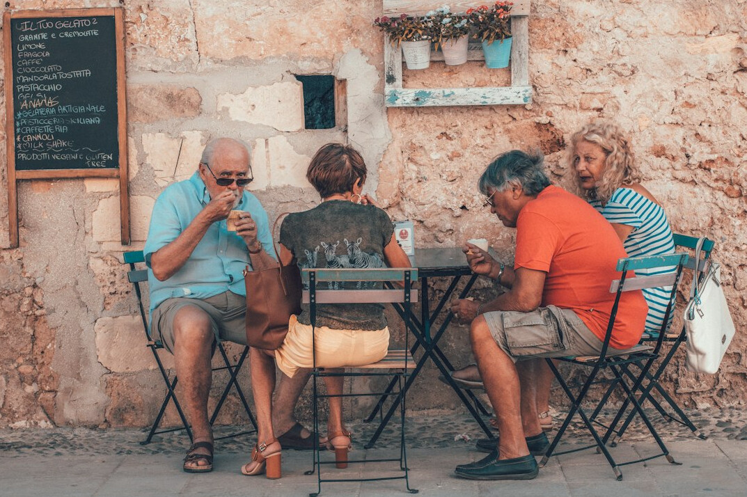 Group of seniors chatting and laughing over coffee at a social meeting
