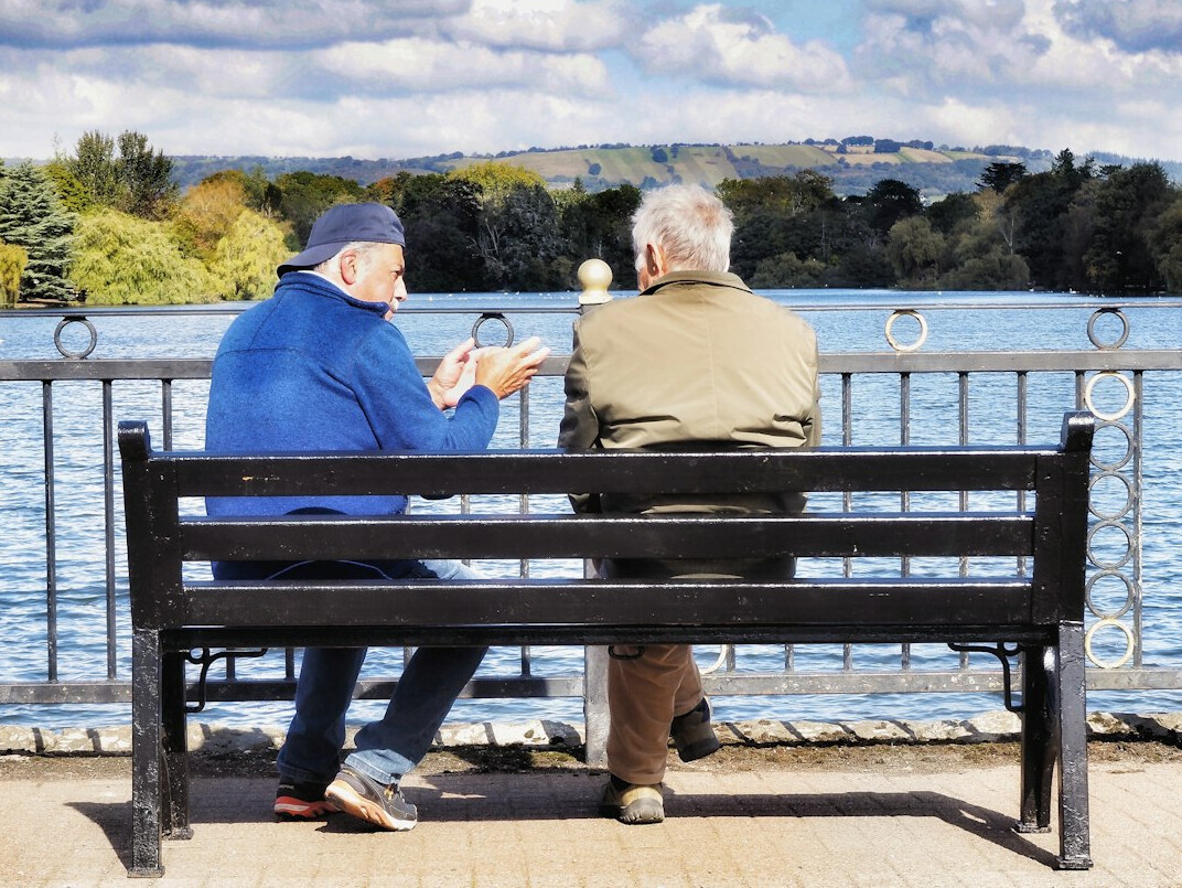 Adult son talking warmly with his elderly mother on a bench